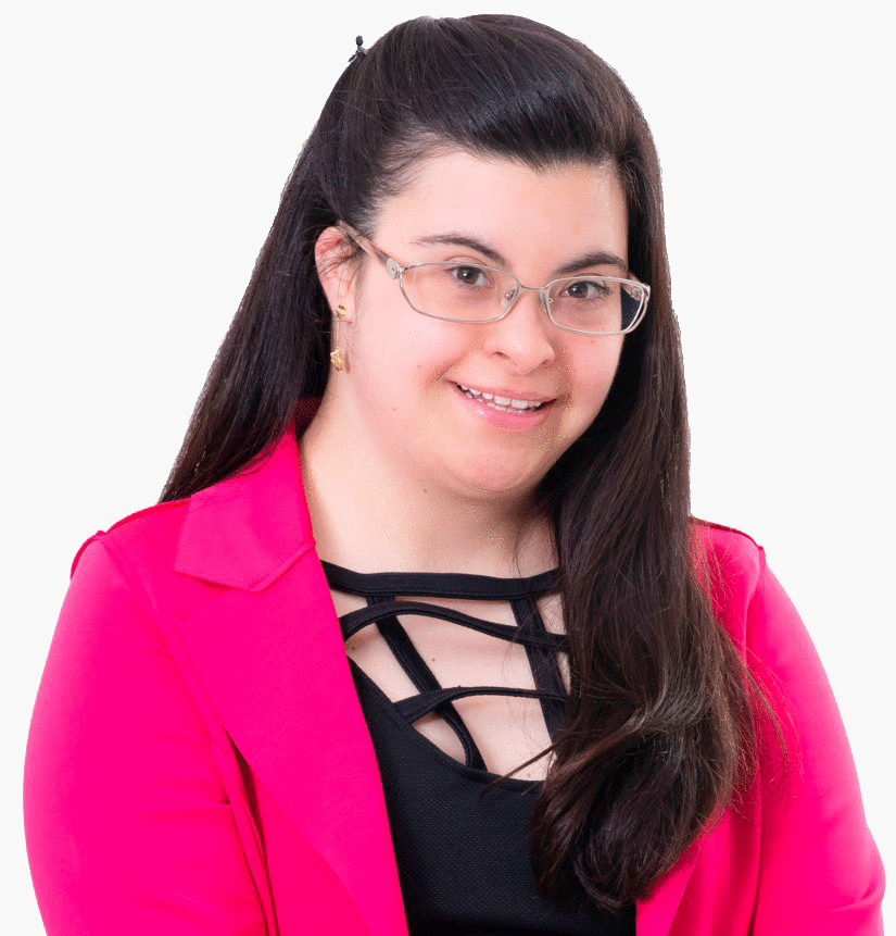 Foto da Fernanda Machado. Ela posa para a foto e sorri. Fernanda tem cabelos castanhos escuros, lisos e longos, usa óculos, usa uma blusa preta e casaco rosa. Os cabelos estão parcialmente presos para trás na parte de cima. 