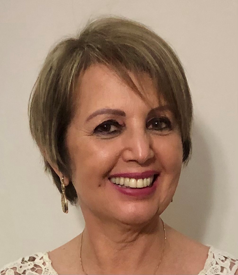 Foto da Odete Ribeiro. Ela posa para foto e sorri. Odete é loira, tem cabelos curtos e lisos, usa brincos e uma blusa estampada.